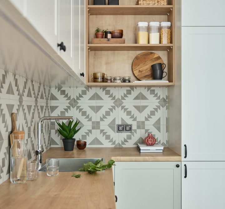 Cuisine moderne avec carrelage géométrique, plan de travail en bois et étagères ouvertes.