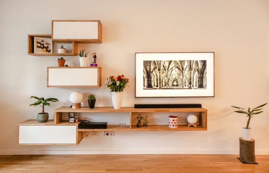 Mobilier moderne en bois avec étagères, plante, fleurs et une œuvre d'art au mur.