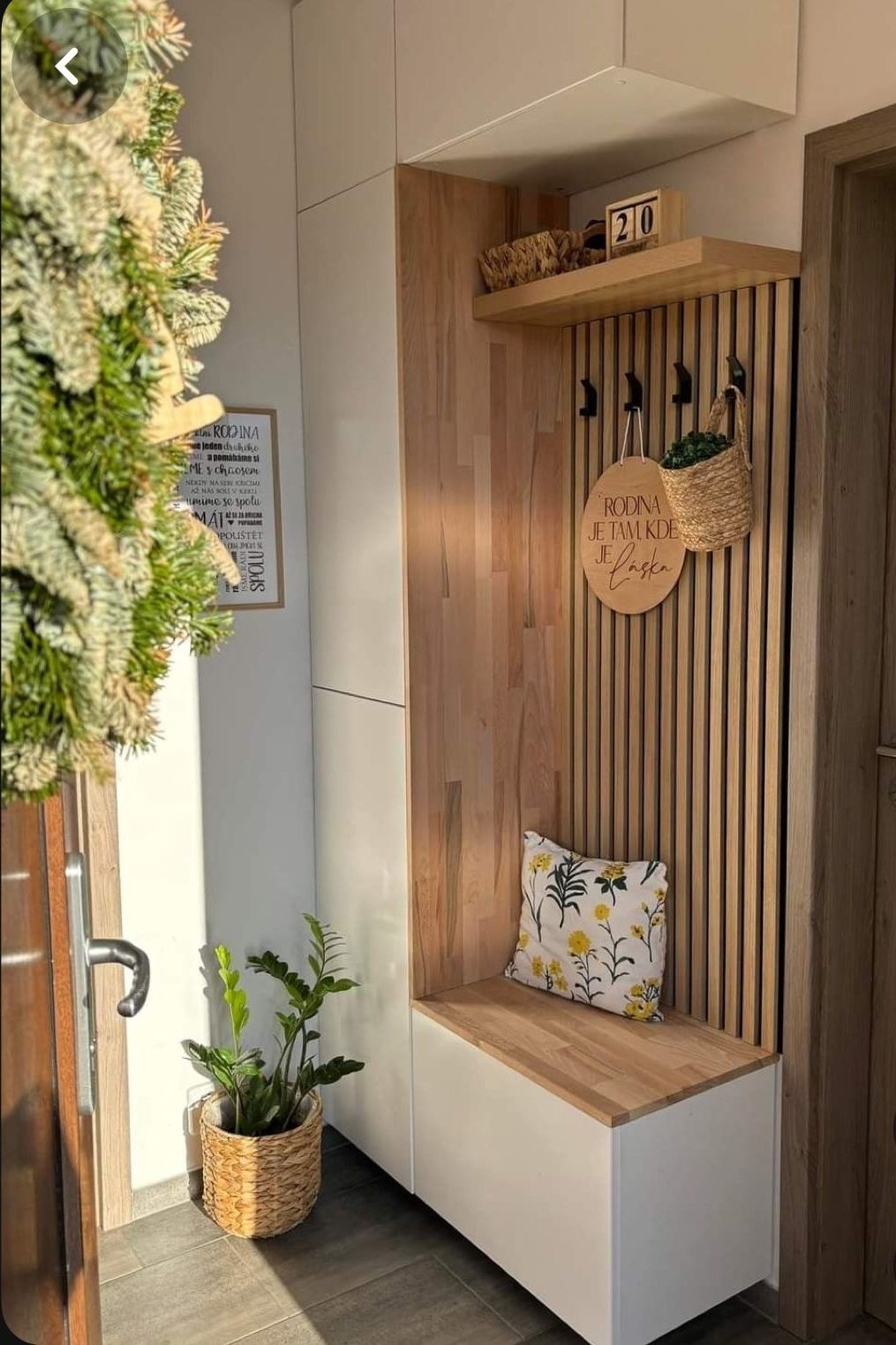 Entrée avec banc en bois, étagères, porte-manteaux et plante en pot.
