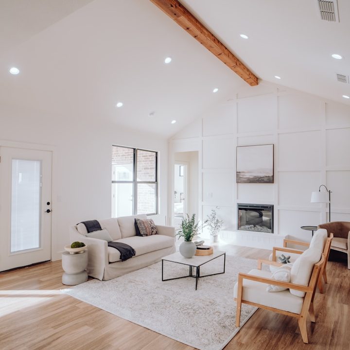 Salon lumineux avec un canapé, des chaises, une table basse et une cheminée.