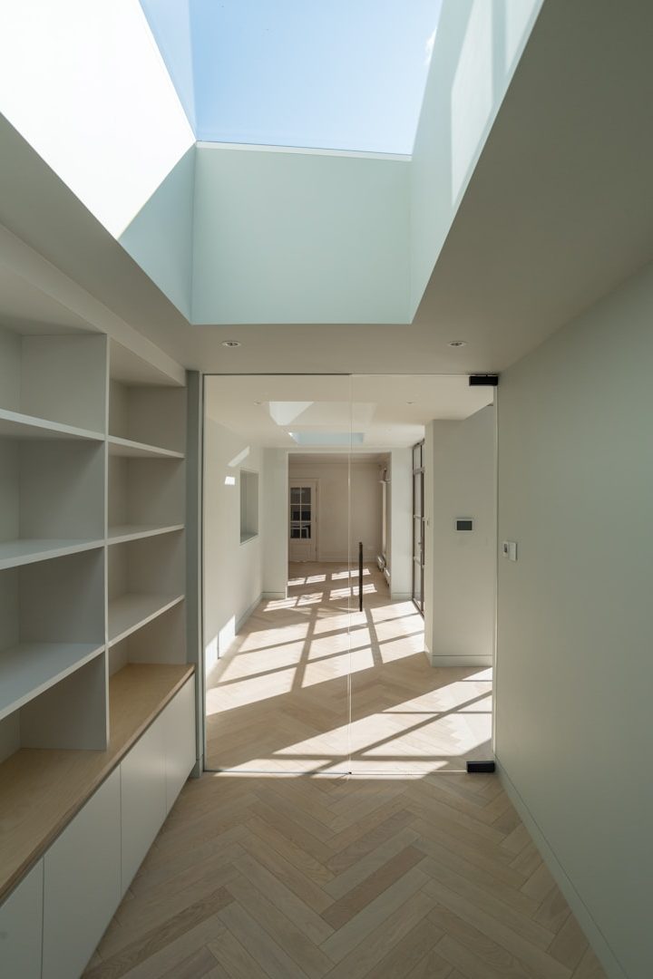 Aménagement espace dressing - Intësia Design Rezé Intérieur moderne et lumineux avec un toit en verre et des étagères blanches.