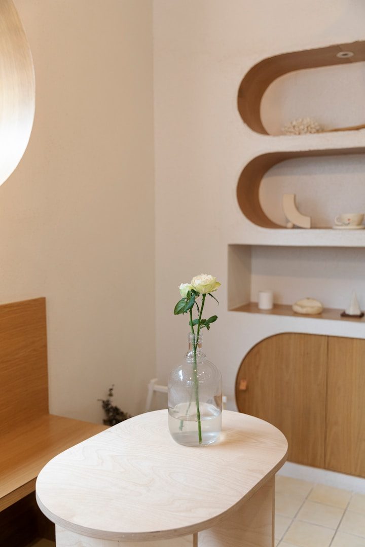 Vase avec une rose sur une table, décor intérieur moderne et lumineux.